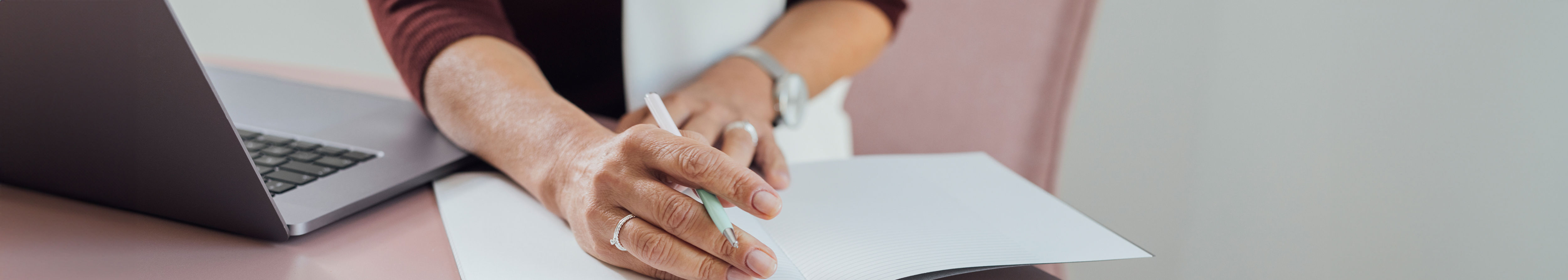 A woman's hand on a notebook with a pen